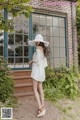 A woman wearing a white dress and a white hat.