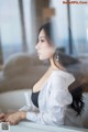 A woman in a white shirt sitting on a window sill.