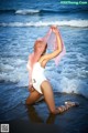 A woman in a white bathing suit sitting on the beach.