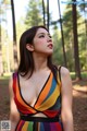 A woman in a colorful dress standing in the woods.