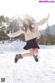 A woman is jumping in the air in the snow.