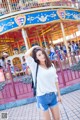 A woman standing in front of a carousel at a carnival.