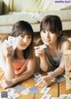 Two young women laying on the floor playing cards.