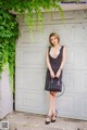 A woman standing in front of a garage door holding a handbag.