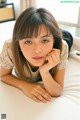 A young woman laying on a bed with her hand on her chin.