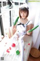 A woman in a maid outfit holding a cucumber.