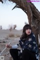 A woman sitting under a tree holding a stick.