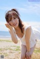 A woman in a white dress posing on a beach.