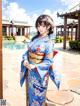 A woman in a blue kimono standing in front of a building.