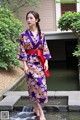 A woman in a purple kimono standing in a pond.