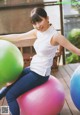 A woman sitting on top of a pink and blue ball.