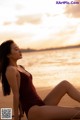 A woman in a red bathing suit sitting on the beach.