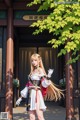 A woman with long blonde hair standing in front of a building.