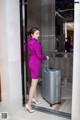 A woman in a purple suit with a suitcase.