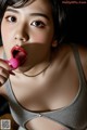 A woman holding a pink toy in her mouth.