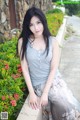 A woman sitting on a stone wall next to a bush.