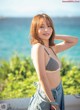 A woman in a bikini posing by the ocean.