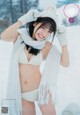 A woman in a white bikini and a white hat in the snow.